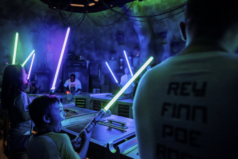 Experiencias interactivas de Star Wars en Disney Niños construyendo sables de luz en una experiencia Star Wars dentro de Disney